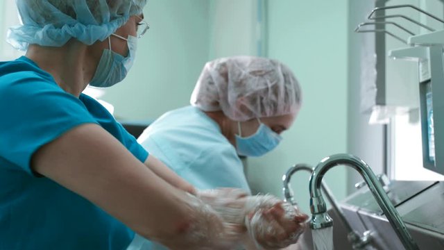 Doctors surgeon in robe washes hands in washbasin before surgery