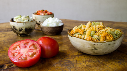 Fresh ingredients for cooking: pasta, tomato, red pepper, onion, and eggplant