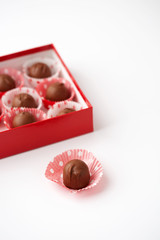 Red box of chocolate covered cherries in red and white polka dot papers.  One isolated in front.  White background with room for text.