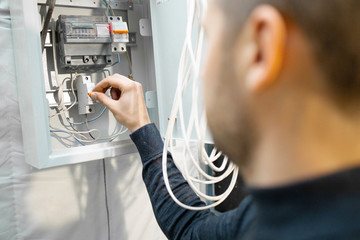 Dangerous job with electricity. Electrician repairing electrical box and installing energy saving meter. Electrician stands near the electric box. - 311799073