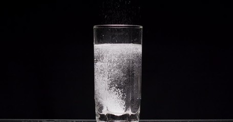 patient throws aspirin into a glass of water on a black background