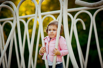 Obraz premium a small, beautiful girl in pink clothes and sunglasses, walking in the Park