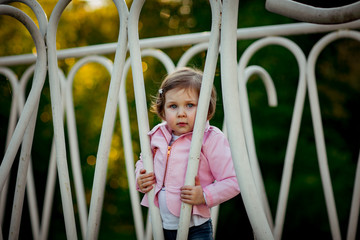 Obraz premium a small, beautiful girl in pink clothes and sunglasses, walking in the Park
