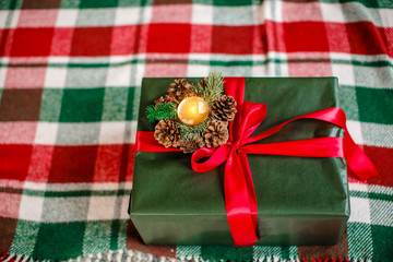 green gift box with a red ribbon lies on a plaid