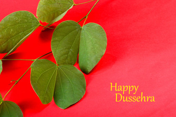 Indian Festival Dussehra, showing golden leaf on red background. Greeting card.