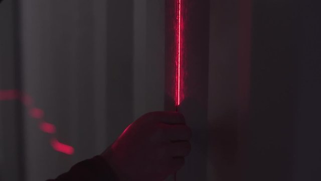 Man's silhouette holding the thick thread on the wall with barcode scanner's red line in the dark. Stock footage. Close-up