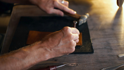 Tanner holding crafting tool and working.