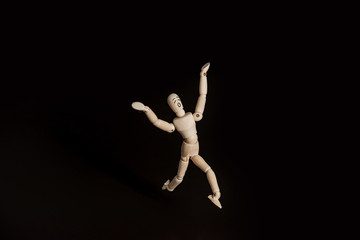 Fototapeta na wymiar Gestalt a wooden figure of a man running in terror against a black background