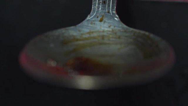 Heroin bubbles cooking in metal spoon isolated macro in dimly lit area