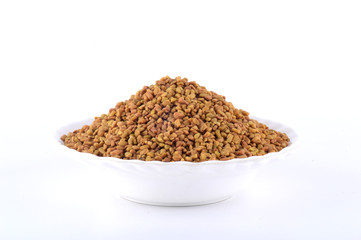 Fenugreek seeds in white plate isolated on white background