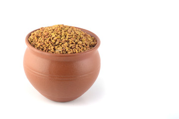 Fenugreek seeds in clay pot isolated on white background