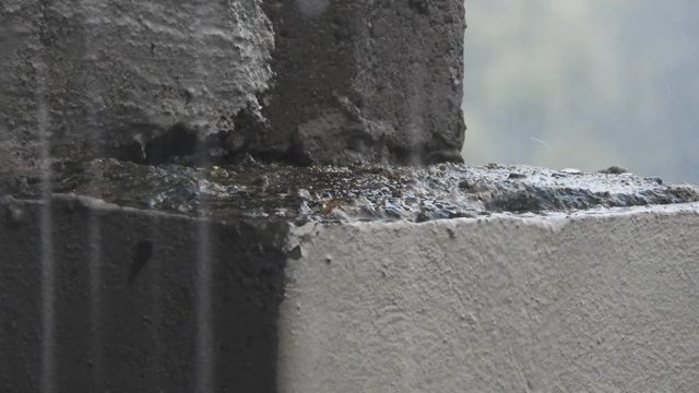 Rain drops and hailstones falling and dripping on plaster and building bricks during a thunderstorm.