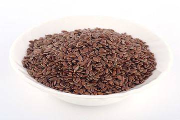 close up of flax seeds in white plate isolated on white background