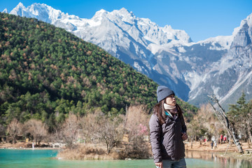 Fototapeta na wymiar Young woman traveler traveling at Blue Moon Valley, landmark and popular spot inside the Jade Dragon Snow Mountain Scenic Area, near Lijiang Old Town. Lijiang, Yunnan, China. Solo travel concept