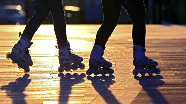 silhouette of two pairs of legs on roller skates