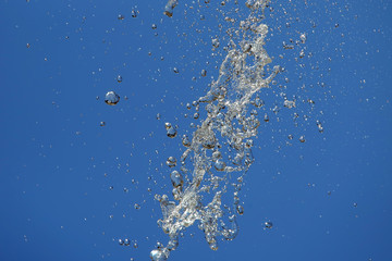 Splashes of flying water from the fountain against the blue sky