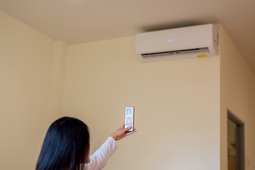 Hands woman using remote control to activating 25 degrees celsius,Concept save energy and save world