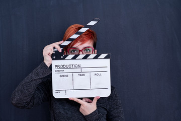 redhead woman holding movie clapper