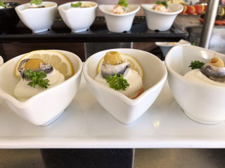 In white salad bowls a fish appetizer at a buffet. Side view, horizontal, close-up. Concept of buffet and healthy food.