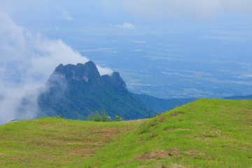 Green grass and Clouds cover mountain tops at autumn day time in thailand