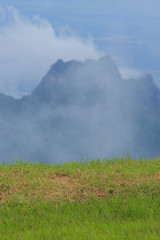 Green grass and Clouds cover mountain tops at autumn day time in thailand