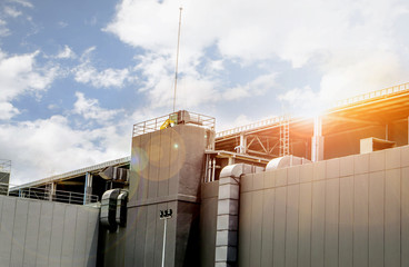 Exhaust and air conditioner ducts for support factory building under the bright of sun and blue sky.