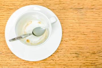 Top view of Stain of coffee in white cups and coffee spoon with saucer on wooden table.