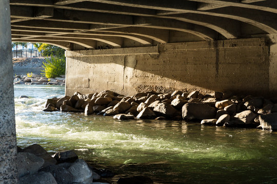 Beautiful light over green rushing water under a bridge on the Truckee