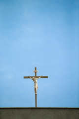 Catholic Church's Statue of jesus on cross against blue sky, top of the world.