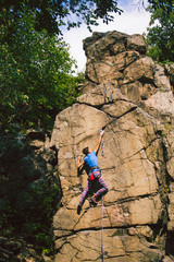 Fototapeta premium The girl climbs the granite rock.