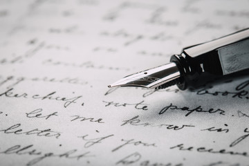 Fototapeta premium Fountain pen on an ancient handwritten letter. Old story. Retro style.