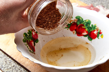 Cooking. Pouring spices from glass bottle into a plate with sunflower oil