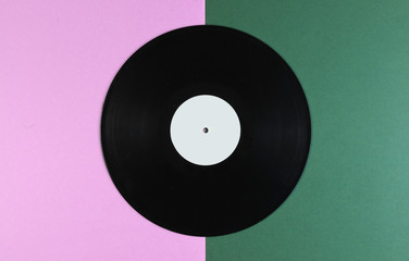 Vinyl record on a green-pink background. Retro style. Top view.