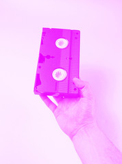 Male hand holds retro video cassette. Dotone effect