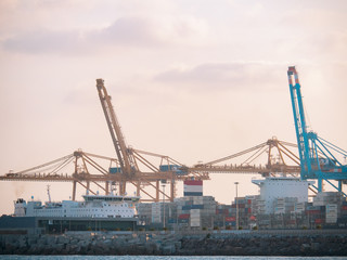 Fototapeta na wymiar Barcelona, Spain - august 2019: industrial harbour in Barcelona, long view. Ships at wharf. Big cargo cranes loading bulks on ships. Mediterranean sea. Selective soft focus. Blurred background