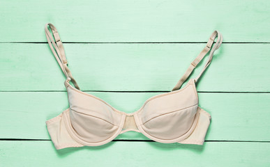 Female bra on green wooden background. Top view