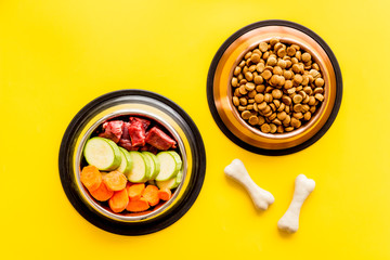 Ingredients of dry feed for dogs - meat, vegetables - near bones on yellow background top view