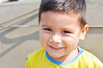 Happy latin little boy. Urban background.