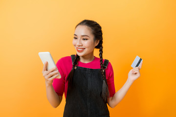 happy asian woman holding credit card and smartphone on colourful background.