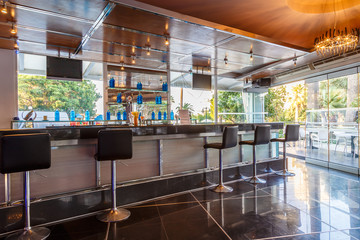 lounge bar of modern European resort hotel, interior with terrace, tables, lighting. Rhodes, Greece