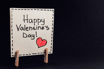 The sticker with the greeting happy Valentines day on the clothespin on a dark background. - 311828260