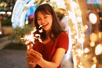 Asian woman holding sparkle fireworks in Christmas party.