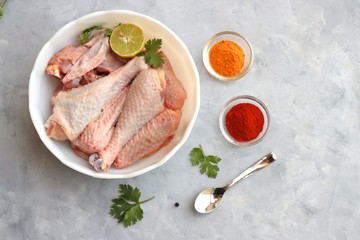 Clean and Raw Free range or country chicken carved in parts in a bowl with Indian spices and cooking ingredients. Along with copy space