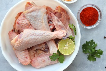 Clean and Raw Free range or country chicken carved in parts in a bowl with Indian spices and cooking ingredients. Along with copy space