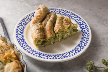 Greek pie spanakopita  over concrete  background. Ideas and recipes for vegetarian or vegan  Spinach Pie from fillo pastry cut in slices. Copy space. Top view or flat lay.