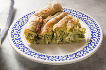 Greek pie spanakopita  over concrete  background. Ideas and recipes for vegetarian or vegan  Spinach Pie from fillo pastry cut in slices. Copy space. Top view or flat lay.