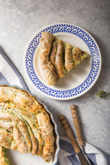 Greek pie spanakopita  over concrete  background. Ideas and recipes for vegetarian or vegan  Spinach Pie from fillo pastry cut in slices. Copy space. Top view or flat lay.