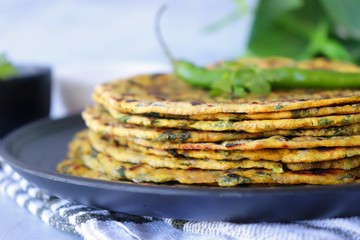 A Food called Methi paratha or Methi thepla is a Indian breakfast dish served with curd and ketchup. with copy space.