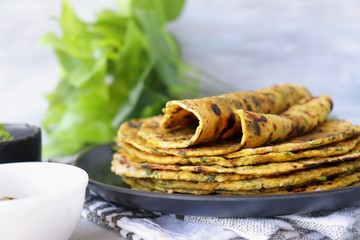 A Food called Methi paratha or Methi thepla is a Indian breakfast dish served with curd and ketchup. with copy space.