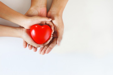 Adult and child hands holding red heart, health care ,love and family concept.